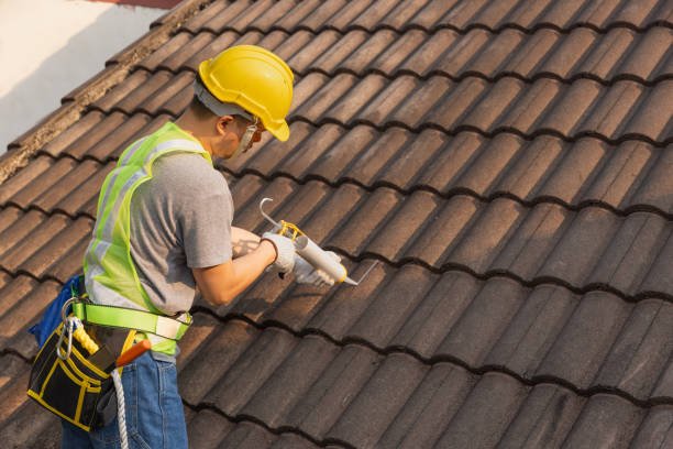Worker man using silicone sealant adhesive  to fix crack of the old tile roof.
